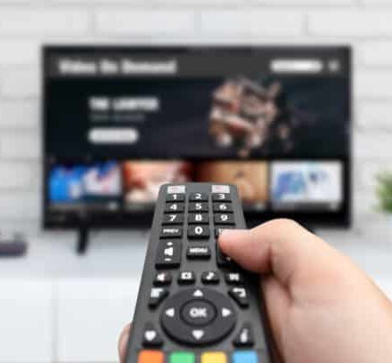 Man watching TV, remote control in hand. VOD service on TV