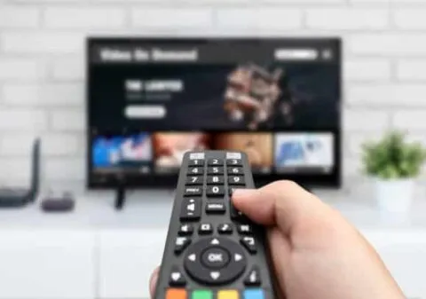 Man watching TV, remote control in hand. VOD service on TV